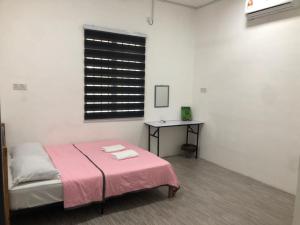 丰盛港Rasa Sayang Homestay Mersing的一间卧室配有一张带粉色毯子和桌子的床。