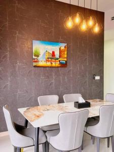 八打灵再也Family Gathering with Bathtub in Icon City, 12 Pax near Bandar Sunway的一间用餐室,配有白色椅子和墙上的绘画作品