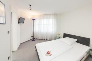 沃尔夫斯堡Novum Hotel Strijewski - Apartments的卧室配有白色的床和电视