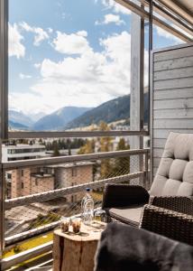 达沃斯美隆达沃斯瑞士山庄度假酒店的阳台配有桌椅,享有风景。