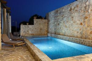 赫瓦尔Villa Vito的一座带石墙和蓝色游泳池的游泳池