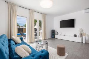 罗波里卡Cosy holiday home Infinity with pool and BBQ的客厅配有蓝色的沙发和电视
