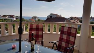 罗戈兹尼察Villa Stella的阳台上配有带2把椅子和酒杯的桌子