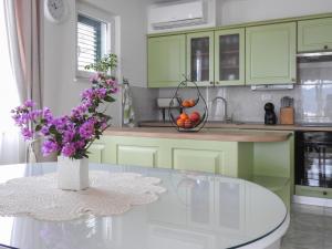 维甘Apartments Klara的厨房配有绿色橱柜和紫色花卉桌