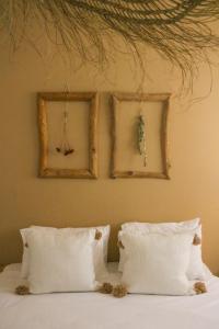 Metsoke DragotMetzoke Dragot Travelers Village的一张带白色枕头的床和墙上的两张照片