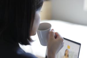 东京东京大冢超级酒店 的女人在电脑前拿着咖啡杯