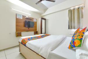 艾哈迈达巴德FabHotel Vishwa的卧室配有一张床铺,墙上配有电视