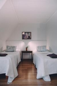 韦克叙Vääksyn Apteekinmajoitus的客房设有两张带白色床单和桌子的床。