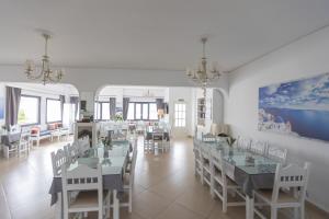 梅加洛克里圣托里尼之星酒店的用餐室配有白色的桌子和白色的椅子