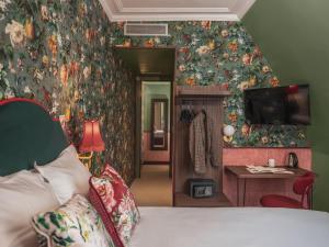 巴黎布列塔尼酒店的一间卧室设有床铺,墙上有鲜花