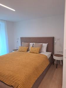 帕兰加Kurortas Apartments的一间卧室配有一张带橙色棉被和枕头的床