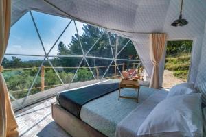 Rachesluxury dome tents ikaria ap'esso的一间卧室设有一张床和一个大型玻璃窗