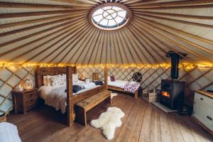SheenScaldersitch Farm Boutique Camping Tipi with private wood fired hot tub的蒙古包内一间卧室,配有一张床和炉灶