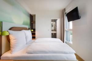 美因河畔法兰克福LyvInn Hotel Frankfurt Messe的一间卧室配有2张白色的床和平面电视