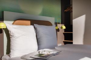 美因河畔法兰克福LyvInn Hotel Frankfurt Messe的一张带白色枕头的床和一本书