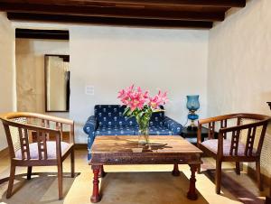 钱德加尔The Kaptain's Retreat的客厅配有蓝色的沙发和桌子上的花瓶