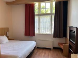 蒂尔堡Onderwijshotel De Rooi Pannen Tilburg的一间卧室设有一张床和一个大窗户