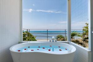 恩纳海まで徒歩1分 沖縄でも珍しい絶景ホテル 贅沢プライベートビーチ付き ビーチルーム的带浴缸的浴室,享有海景。