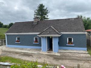 利特里姆Clinton’s cottage的蓝色的房子,设有两扇窗户和屋顶