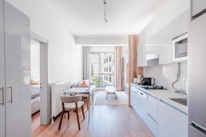 伊斯坦布尔Homie Suites - Newly-constructed Apartment Complex in Beşiktaş的厨房配有白色橱柜和桌椅