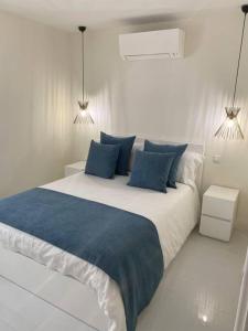 Saint-AntoineCap d ail Appartement aux portes de Monaco的白色卧室配有一张带蓝色枕头的大床