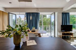 宾茨FeWo Prora - Luft und Loft的一间带大桌子的客厅和一间带蓝窗帘的用餐室