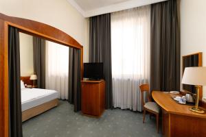 布达佩斯Danubius Hotel Hungaria City Center的酒店客房配有一张床、一张书桌和一台电视。