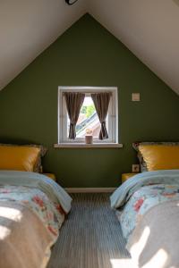 库尔迪加i’dille Brīvdienu māja的绿色卧室设有两张床和窗户