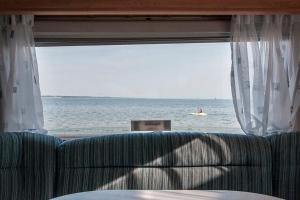 亚斯塔尔尼亚Przyczepa w pierwszej linii brzegowej - Kemping Molo Surf的带沙发的窗户享有海景。