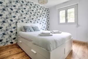 圣卡勒吉勒多Les Ebihens - Studio et chambre indépendante的一间卧室设有一张大床,墙壁覆盖着灰色和白色