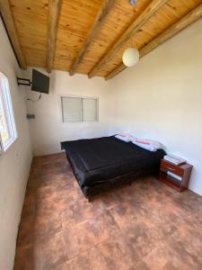 圣拉斐尔Cabañas Pausa Mendocina的一间设有黑色床的卧室,位于一个拥有木制天花板的房间