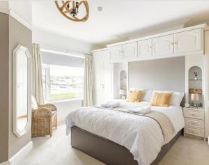 波特拉什Larkhill House的白色的卧室设有一张大床和一个窗户