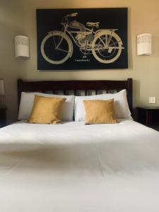 Gamarde-les-Bainsl'auberge的一张带两个枕头的床和一张墙上的自行车照片