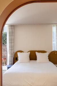 比亚里茨圣朱利安酒店的一间卧室配有一张带白色床单的床和一扇窗户。