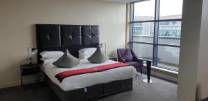威布里治力推布鲁克兰酒店&SPA的一间卧室配有一张带黑色床头板的床和窗户
