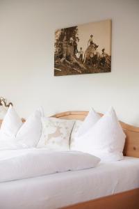 雷特温克尔豪斯洛佛塔尔宾馆的一张带白色枕头的床和墙上的绘画