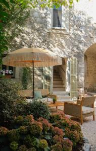 卢河畔拉科尔L'Abbaye Hôtel的大楼前的带椅子和遮阳伞的天井