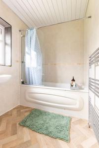 CranfordSpacious 3BHK near Heathrow的带浴缸和绿色地毯的浴室