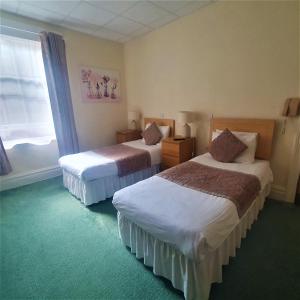 伯恩茅斯伯利府酒店的酒店客房设有两张床和窗户。