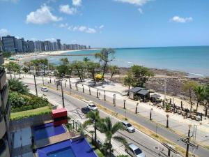 福塔莱萨Lindo Flat Beira Mar 401的享有海滩美景,路边可停放汽车