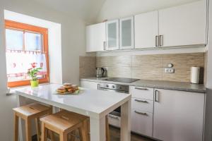 佐尔尼耶戈迪Apartmaji Tina的厨房配有白色橱柜和柜台上的一盘水果