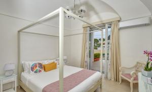 卡普里Villa Giardini Luxury Room的一间卧室设有一张天蓬床和一个阳台