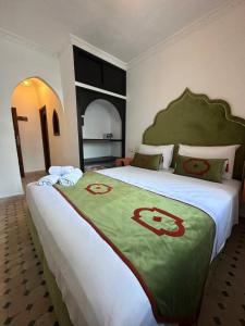丹吉尔Kasba blanca的一间卧室配有一张大床,提供绿色和白色的毯子