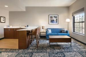 罗利Four Points by Sheraton Raleigh Arena的客厅配有蓝色的沙发和桌子
