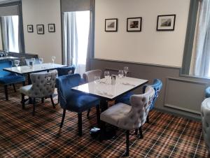 瑟索Royal Thurso Hotel的一间设有两张桌子和蓝椅的用餐室