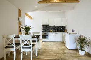 穆希纳Apartament Abra 1 Rynek 8的厨房配有白色橱柜和桌椅