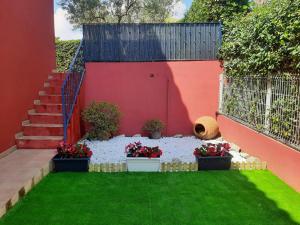 佩尼斯科拉URBANIZACION MIRAMAR PENISCOLA的种有盆栽植物和红色墙壁的花园