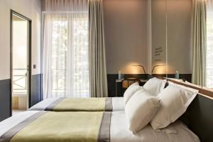 巴黎加斯顿酒店的卧室配有带白色枕头的大床