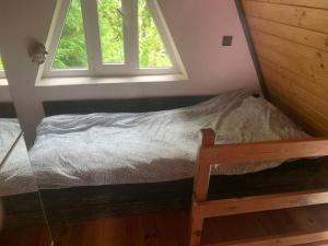SznurkiDomek na Kaszubach 40 min od Gdańska的一张小床,位于带两个窗户的房间
