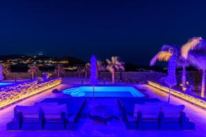 卡拉法蒂斯Aurora Mykonos Villas的游泳池,晚上配有椅子和棕榈树